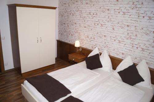 a white bed in a room with a brick wall at Pension DOBERNIG - CONTACTLESS CHECK IN/STAY in Klagenfurt