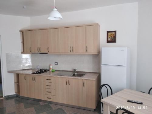 a kitchen with wooden cabinets and a sink and a refrigerator at Casa Prifti in Vlorë