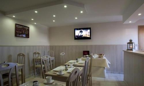 ルーセラーレにあるHotel Chamdorのテーブルと椅子、壁掛けテレビ付きのレストラン