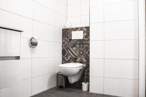 a bathroom with a toilet in a white tiled wall at Van Doremaele Luxury Guesthouse in Velddriel