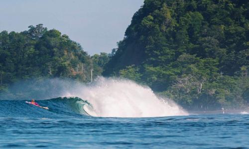 a boat riding a large wave in the ocean at Beach Break Resort & CR Surf Camp in Jacó