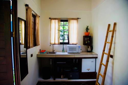 eine Küche mit einer Theke mit einer Mikrowelle und einem Fenster in der Unterkunft Cabinas D’Val in Uvita