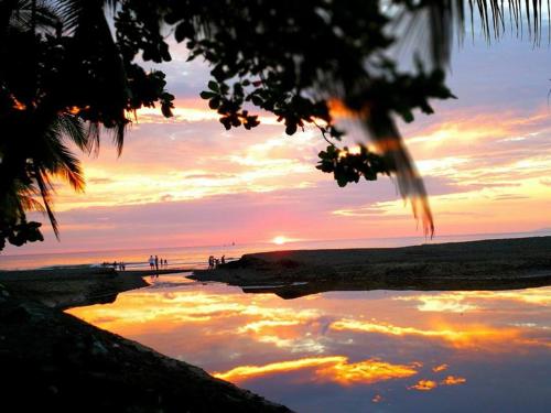 a reflection of a sunset in a body of water at Beach Break Resort & CR Surf Camp in Jacó