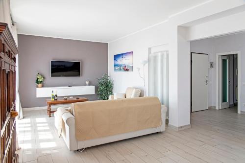a living room with a couch and a tv on a wall at Appartamento Alex Vista Mare in Lido di Camaiore