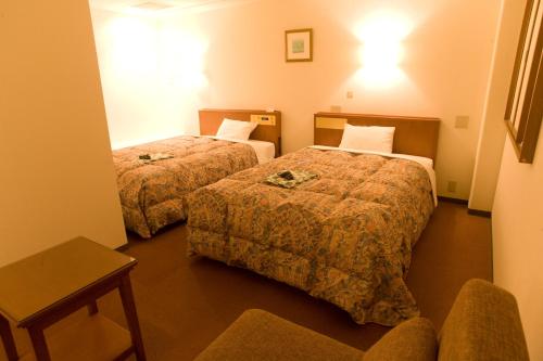 a hotel room with two beds and a chair at Kuretake-Inn Iwata in Iwata
