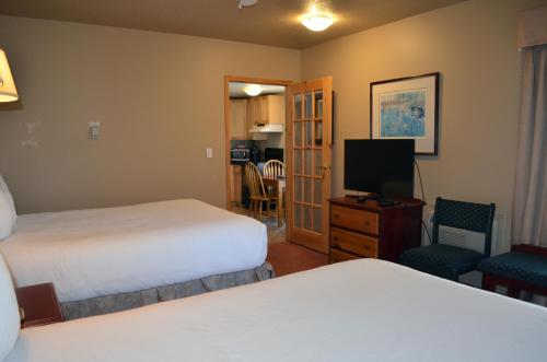 a hotel room with two beds and a flat screen tv at Waterton Lakes Lodge Resort in Waterton Park