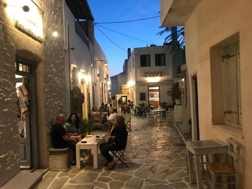 un groupe de personnes assises à une table dans une ruelle dans l'établissement Hotel Messaria, à Kythnos