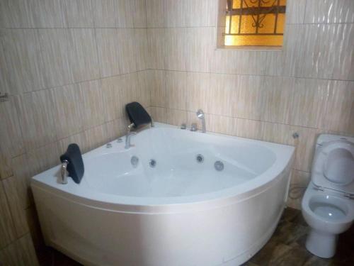 El baño incluye bañera blanca y aseo. en Fort Breeze Hotel, en Fort Portal