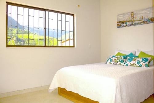 a bedroom with a white bed and a window at Apartamentos Primavera in Jardin