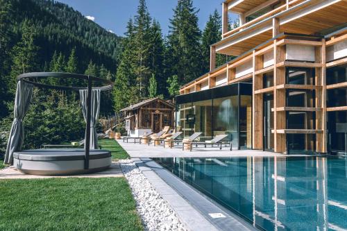 a house with a swimming pool next to a house at Hotel Cristallo - Wellness Mountain Living in La Villa