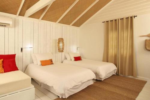 2 camas en una habitación con almohadas blancas y rojas en Hansar Casuarina Cha am, en Puk Tian