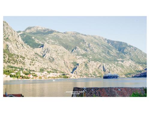 a boat in a body of water with mountains at Kampe Apartments in Kotor