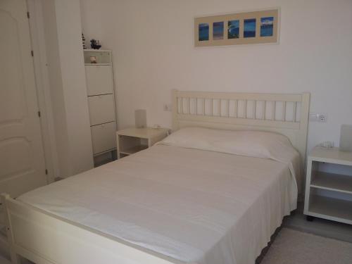 um quarto com uma cama branca e uma colcha branca em Apartamento Vistas Espectaculares al Mar em Carboneras