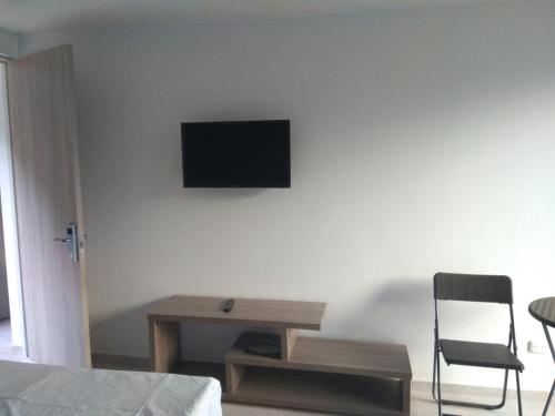 a bedroom with a desk and a television on the wall at Okawango Hotel in Girardot