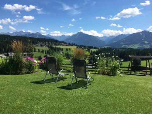 two chairs sitting on a lawn with mountains in the background at Haus Sonnleitner in Ramsau am Dachstein