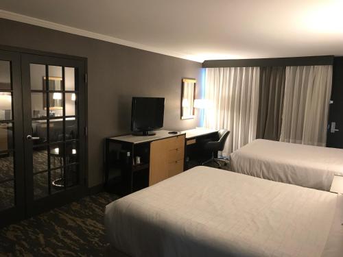 a hotel room with two beds and a desk with a television at Wyndham Lancaster Resort and Convention Center in Lancaster