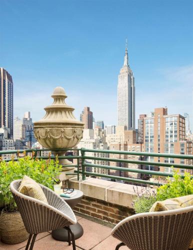 a balcony with chairs and a view of a city at The Shelburne Sonesta New York in New York