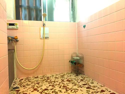 um chuveiro de azulejos cor-de-rosa com uma mangueira na casa de banho em Tsukubo-gun - House / Vacation STAY 34603 em Hayashima