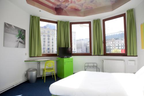 - une chambre avec des rideaux verts, un lit et des fenêtres dans l'établissement Hotel Siru, à Bruxelles