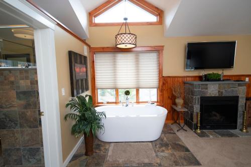 ein Bad mit einer Badewanne und einem Kamin in der Unterkunft Solitude Village at Okemo in Ludlow
