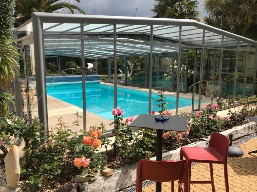 a patio with a table and chairs next to a swimming pool at Aigue Marine Logis Hotel et Restaurant in Tréguier