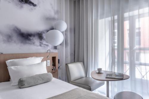 a bedroom with a bed and a chair and a table at Le Grand Balcon Hotel in Toulouse