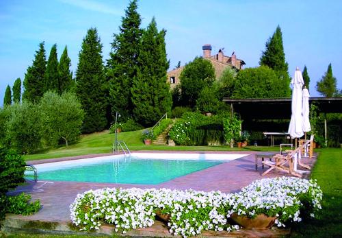 a swimming pool with a umbrella and some white flowers at Le Traverse in Pienza