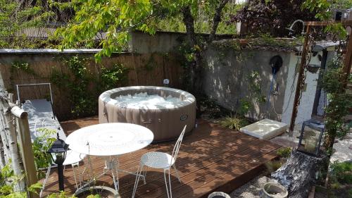 a patio with a hot tub and a table and chairs at Les Iris Chambres d’hôte in Niedermorschwihr
