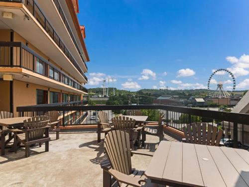 un balcón con mesas y sillas y una noria en Mountain Vista Inn & Suites - Parkway, en Pigeon Forge