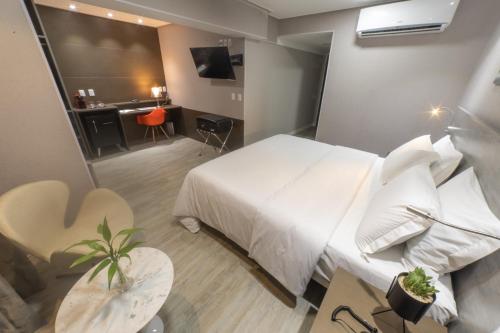 a hotel room with a white bed and a desk at Intercity Campina Grande Citymix in Campina Grande