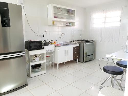 eine weiße Küche mit einem Kühlschrank und einer Spüle in der Unterkunft Solar Teixeira Residencial in Porto De Galinhas