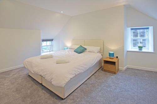 sypialnia z dużym białym łóżkiem z nocnym stolikiem w obiekcie Modern Commercial Street Maisonette w mieście Lerwick