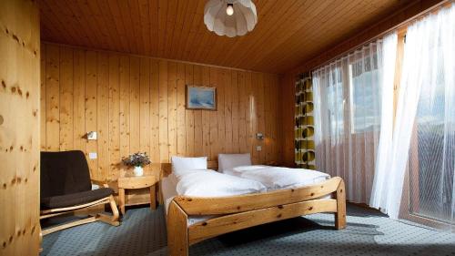 a bedroom with a bed and a chair and a window at Hotel Alpfrieden in Bettmeralp