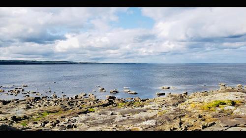 a large body of water with rocks and boats at Spectacular ocean views & minutes to Cliffs- Clahane Shore Lodge in Liscannor