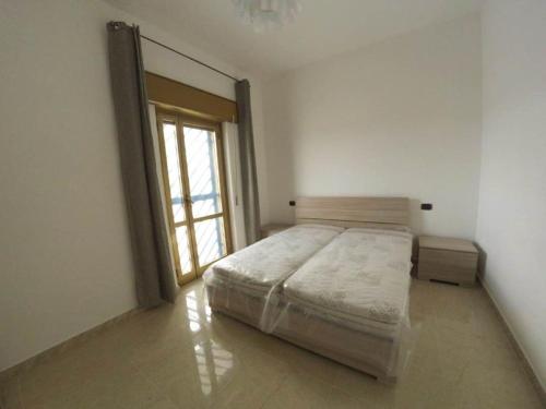ein weißes Schlafzimmer mit einem Bett und einem Fenster in der Unterkunft Villa Blu - Torre Ovo in Monacizzo