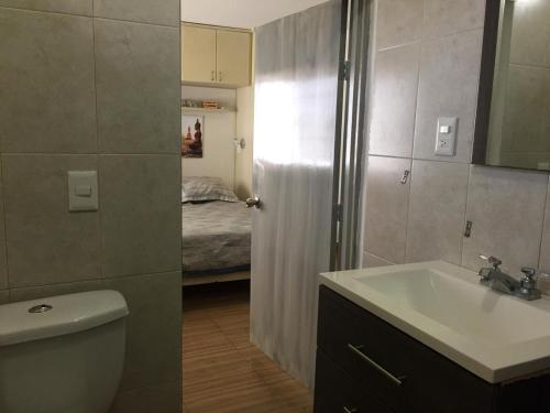 a bathroom with a sink and a toilet and a bed at Zona Dorada Mazatlan in Mazatlán