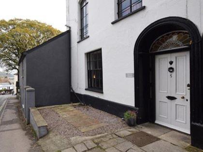 a white building with a white door on a street at Burton House Apartment in Lyme Regis