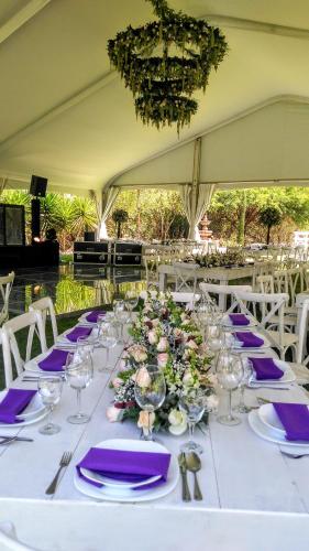 a long white table with purple napkins and glasses at Hotel Spa Hacienda Real la Nogalera in Tequisquiapan