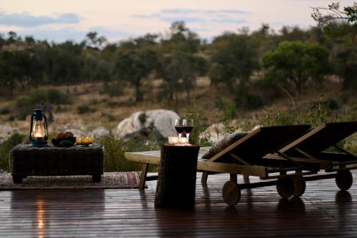 einen Tisch mit zwei Kerzen und ein Glas Wein in der Unterkunft Ivory Wilderness River Rock Lodge in Klaserie Private Nature Reserve