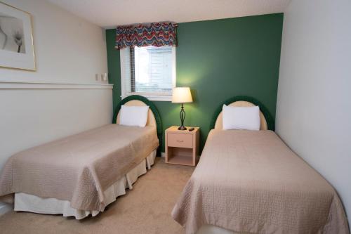 two beds in a room with green walls at Winterplace on Okemo Mountain in Ludlow