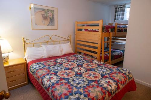 a bedroom with a bed and two bunk beds at Winterplace on Okemo Mountain in Ludlow