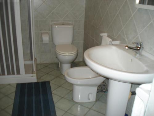 a white bathroom with a toilet and a sink at Agriturismo La Grevillea in Riposto