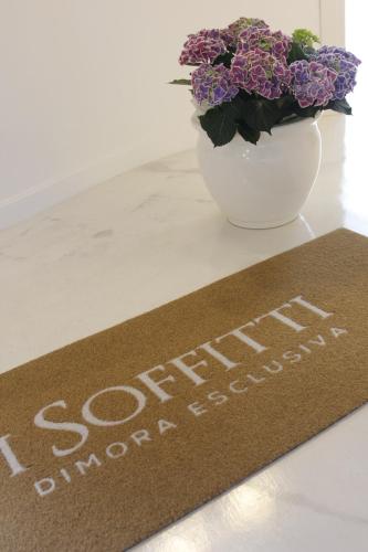 a welcome mat on a table with a vase of flowers at I Soffitti Dimora Esclusiva in Tropea