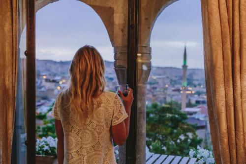 a woman standing in front of a window talking on a cell phone at Panoramic Cave Hotel in Göreme