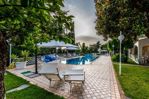 a swimming pool with two chairs and an umbrella at Ischia Dream Sunset in Ischia