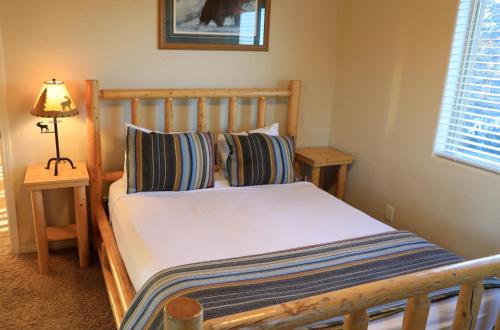 a bedroom with a wooden bed with pillows and a lamp at Zion Ponderosa Ranch Resort in Springdale