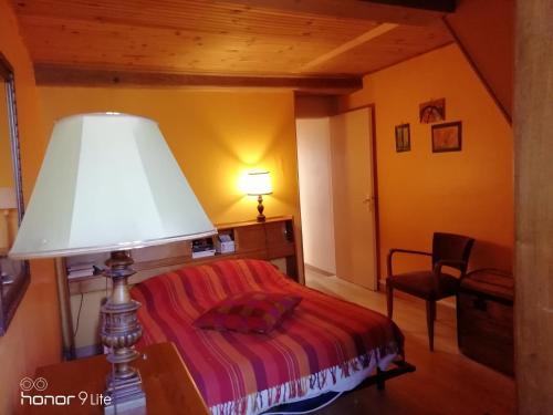 una camera da letto con un letto con una lampada e una sedia di Chambre d hôte le lavoir a Saint-Brisson