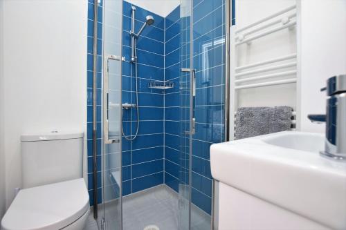 W wyłożonej niebieskimi kafelkami łazience znajduje się toaleta i umywalka. w obiekcie B&B@no2 w mieście Sheringham