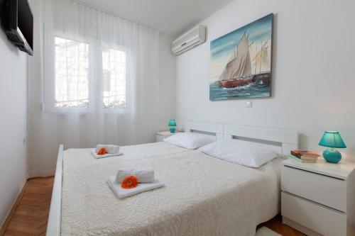 Villa Anja في سبليت: غرفة نوم بيضاء عليها سرير وصحنين