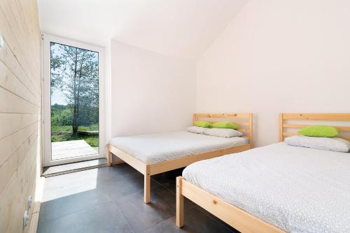 two beds in a room with a window at Naturalny domek z banią in Siedliszcze